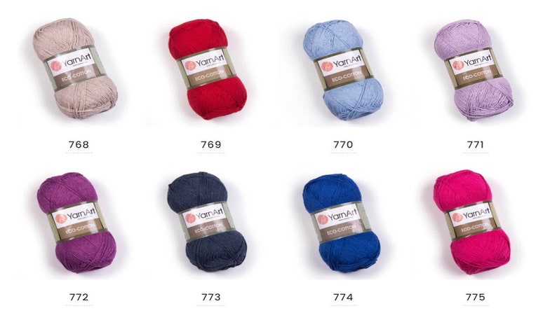 Peut inclure: Assortiment de dix pelotes de fil YarnArt Eco-Cotton de diff&eacute;rentes couleurs, dont beige, rouge, bleu clair, lavande, violet, bleu marine et rose. Chaque pelote porte une &eacute;tiquette avec le nom de la marque "YarnArt" et le texte "Eco-Cotton".