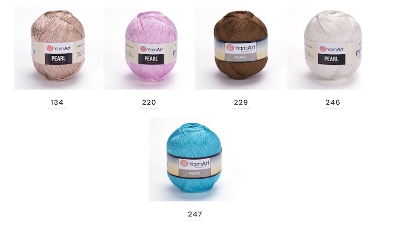 Puede incluir: Cinco ovillos de hilo en diferentes colores: beige, rosa, marr&oacute;n, blanco y turquesa. Cada ovillo tiene una etiqueta que dice "YarnArt PEARL".