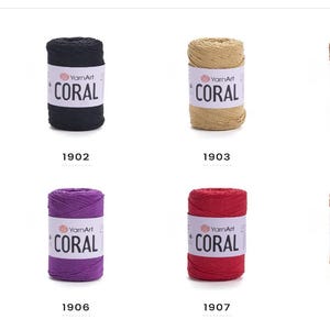Puede incluir: Ocho carretes de hilo en diferentes colores, incluyendo blanco, negro, marr&oacute;n, morado, rojo y naranja. Cada carrete tiene el texto "YarnArt CORAL" impreso en la etiqueta.