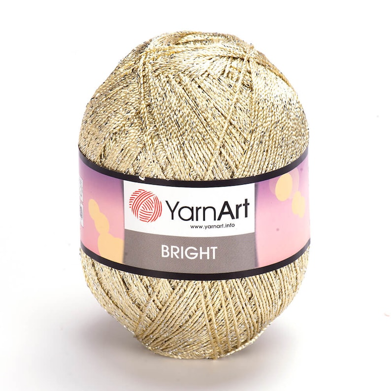 Op de afbeelding: Een bol garen in goud met zilveren glitter, met het label "YarnArt BRIGHT" en de website www.yarnart.info.