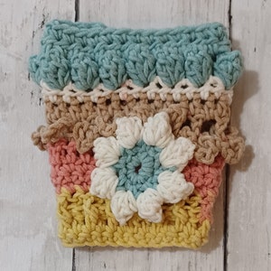 Puede incluir: Funda para maceta de ganchillo multicolor con un diseño azul, marrón, rosa y amarillo.