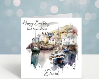 Puede incluir: Tarjeta de cumpleaños con una ilustración en acuarela de un pueblo costero y barcos. La tarjeta dice "Happy Birthday To A Special Son" y "David". Los barcos están en un puerto con edificios en un acantilado al fondo.