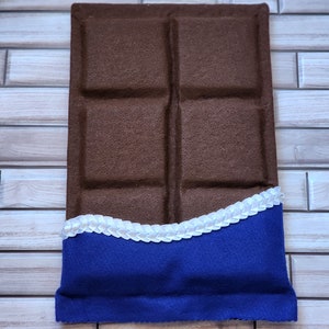 May include: A brown felt chocolate bar pillow with a blue felt wrapper and white felt trim.