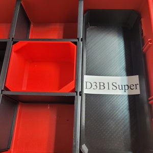 May include: A red toolbox with a black tray insert labeled "D3B1Super". The tray has a textured surface and is divided into multiple compartments.