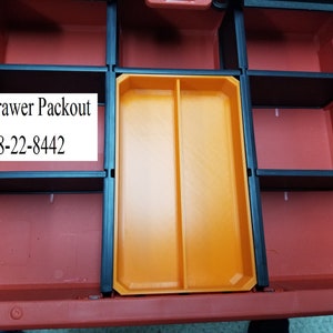 May include: A red and black 2-drawer Packout storage container with an orange tray. The container has multiple compartments and the text "2 Drawer Packout 48-22-8442" is visible.