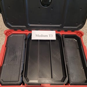 May include: Open red and black tool case with multiple compartments. The case is labeled "Medium T3" and has a black handle. The interior features black storage trays and compartments for organizing tools and equipment.