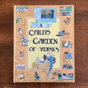 May include: A yellow book with a blue and white illustration of a child's garden of verses by Robert Louis Stevenson. The cover is decorated with various illustrations of children in different scenes.