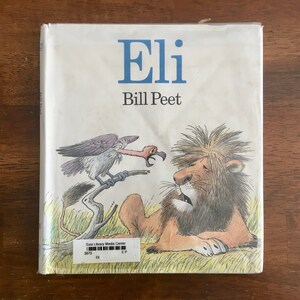 May include: A white book cover with the title "Eli" by Bill Peet. The cover features a cartoon illustration of a lion and a vulture.