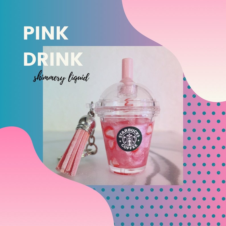 Pode incluir: Um copo de pl&aacute;stico transparente com um l&iacute;quido rosa brilhante e fatias de morango, com o logotipo da Starbucks Coffee. O copo tem uma palhinha e tampa rosa, e est&aacute; preso a um porta-chaves com borla rosa. O texto na imagem diz "PINK DRINK shimmer liquid".