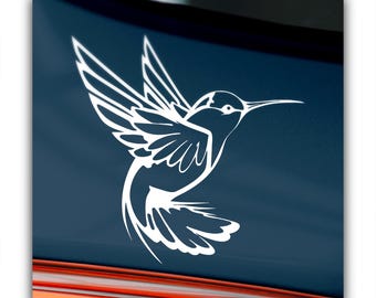 May include: White hummingbird decal in flight, with detailed wing and tail feathers. The decal is set against a dark blue background, creating a striking contrast. The hummingbird's beak is long and slender, and the overall design is clean and modern.