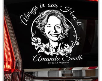 May include: A white vehicle decal with a portrait of a woman encircled by a floral wreath. The text "Always in our Hearts" is above the portrait, with the name "Amanda Smith" and dates below. The decal is designed for a vehicle.