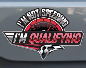 May include: A red and black car sticker with a speedometer and the text "I'm not speeding I'm qualifying".