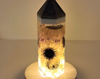 Real Sunflowers in resin tower w/a majestic purple, glittery top. LED wooden light pedestal & wall plug included. Great Sunflower lover gift