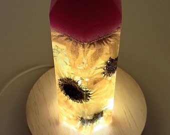 Real Sunflowers in resin tower w/a hot pink, glittery top. LED wooden light pedestal & wall plug included. Great Sunflower lover gift