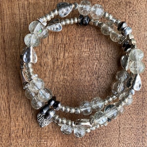 Könnte beinhalten: Ein silbernes Armband mit klaren Glasperlen und silbernen Herzanhängern.