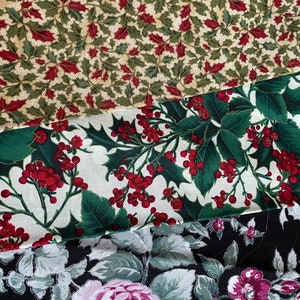 Peut inclure: Gros plan sur trois motifs de tissu. Le tissu supérieur présente un fond beige avec des feuilles vertes et des baies rouges. Le tissu du milieu a un fond blanc avec des feuilles vertes et des baies rouges. Le tissu inférieur a un fond noir avec des fleurs roses et grises.