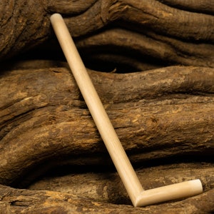 May include: A light brown wooden L-shaped stick resting on a pile of brown tree roots.