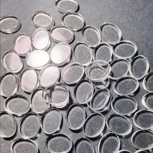 May include: A large quantity of clear glass oval-shaped tiles. The tiles are smooth and translucent.