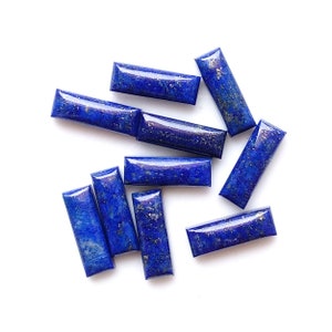 May include: A collection of ten rectangular lapis lazuli gemstone cabochons. The stones are a deep blue color with flecks of gold pyrite.