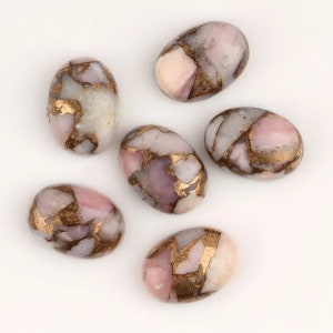 Puede incluir: Seis piedras ovaladas de color rosa y blanco con motas doradas. Las piedras son lisas y pulidas.
