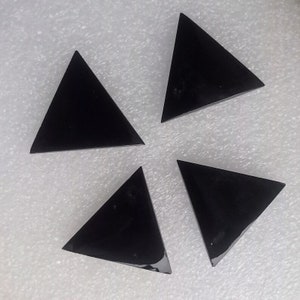 May include: Four black triangular shaped crystal points on a white background.