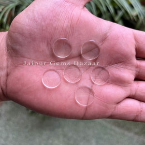 Könnte beinhalten: Sechs runde, flache Cabochons aus klarem Glas auf einer Hand. Jaipur Gems Bazaar steht auf der Hand.