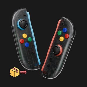 May include: Two transparent black game controllers with colorful buttons. One controller has a blue side, the other has a red side. The buttons are yellow, red, green, and blue. The text "Mail In" is visible.