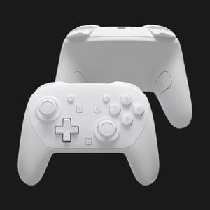 May include: Two white game controllers are displayed against a black background. The controllers have a symmetrical design with buttons, directional pads, and joysticks. The top controller is slightly out of focus, while the bottom controller is in sharp focus.