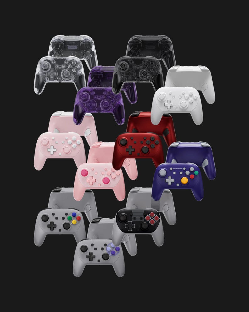 May include: A collection of various game controllers in a variety of colors, including clear, black, white, pink, red, and blue. The controllers have buttons, joysticks, and directional pads.