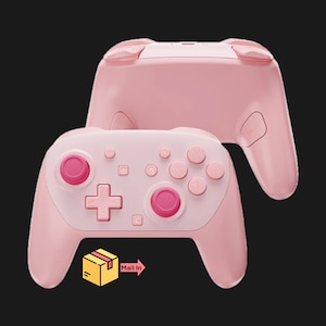 May include: Two pink game controllers are displayed against a black background. The controllers have a light pink body with darker pink buttons. One controller is positioned in front of the other. The image includes a yellow box with the words "Mail In".