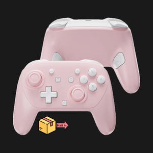 May include: Two pink game controllers with white accents and buttons are displayed against a black background. The controllers have a classic design with a D-pad, face buttons, and analog sticks. The image also includes a graphic of a box with the words "Mail In".