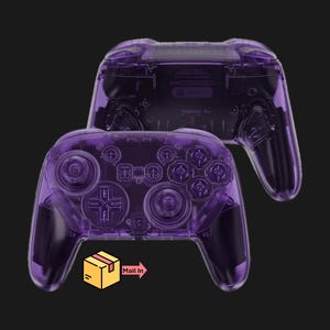 May include: Two transparent purple game controllers are displayed against a black background. The controllers have a clear, see-through design, showcasing the internal components. The controllers have buttons, joysticks, and directional pads.
