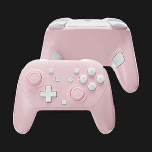 May include: A pink wireless game controller with white accents. The controller features a D-pad, face buttons, and analog sticks. The design includes a second controller in the background, showing the top and back.