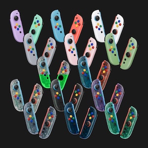 May include: A collection of twenty-four video game controllers arranged in a scattered pattern. The controllers feature various solid and translucent plastic shells in colors including purple, mint, blue, red, white, gray, pink, green, and black.