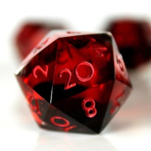 May include: A red twenty-sided die with the numbers 2, 8, 10, and 20 visible. The die is made of clear plastic and has a frosted finish.