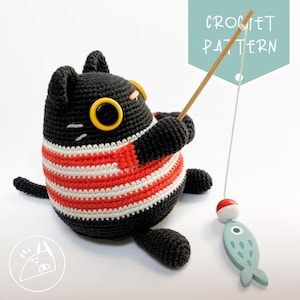 May include: A black crocheted cat wearing a red and white striped shirt is holding a fishing rod with a blue fish on the end. The cat has large yellow eyes and a black nose. The text "CROCHET PATTERN" is written on a light blue background.