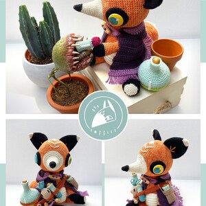 Peut inclure: Un renard en crochet portant une &eacute;charpe violette et tenant une bouteille et un petit renard en crochet. Le renard est assis sur une surface en bois avec une plante en pot en arri&egrave;re-plan.