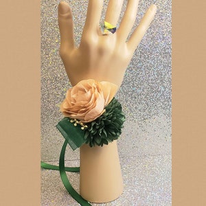 This is a green, dusty rose color corsage with artificial flowers and matching rose gold iridescent ring