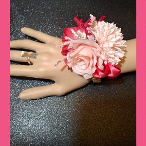This is a beautiful corsage with pink / hot pink artificial flowers. Includes matching adjustable silver tone gem ring.