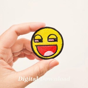 May include: Yellow embroidered iron-on patch with a smiley face with closed eyes and a wide open mouth. The smiley face has a pink tongue.