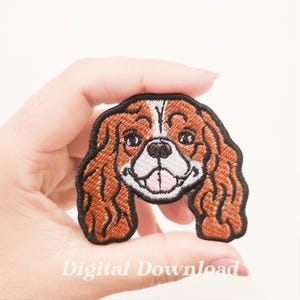 May include: Embroidered patch featuring a Cavalier King Charles Spaniel dog. The patch has brown, white, and black details, with a smiling expression. The text "Digital Download" is at the bottom.
