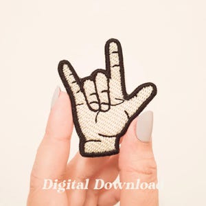 以下が含まれることがあります： 手話で「愛してる」のサインをしている手を描いた、黒と白の刺繍パッチです。