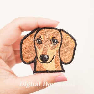 Puede incluir: Parche bordado con la cara de un perro salchicha. El parche tiene un esquema de color marrón y beige con contorno negro. La cara del perro está detallada con ojos negros y una nariz negra. El texto "Digital Download" está en la parte inferior.