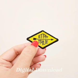 May include: A yellow diamond-shaped iron-on patch with black embroidery. The patch says "Stay True" with an arrow pointing to the right.