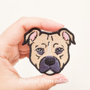 May include: Embroidered patch featuring a tan dog face with black outlines and accents. The dog has a purple nose and dark eyes. The ears are pink. The text "Digital Download" is at the bottom of the image.