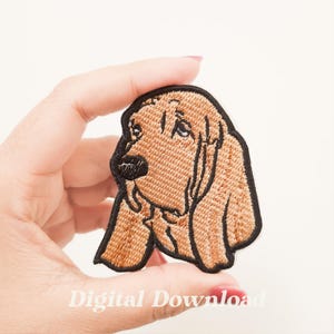 Könnte beinhalten: Gestickter Aufnäher mit einem hellbraunen Bloodhound-Hund mit schwarzer Umrandung. Der Aufnäher wird in einer Hand gehalten und trägt am unteren Rand die Worte "Digital Download". Die Merkmale des Hundes sind detailliert, mit sichtbaren Augen, Nase und Schlappohren.