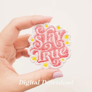 Könnte beinhalten: Ein weißer gestickter Aufnäher mit rosa Hintergrund und gelben Sternen. Der Aufnäher zeigt den Schriftzug "Stay True" in einer stilisierten Schriftart.
