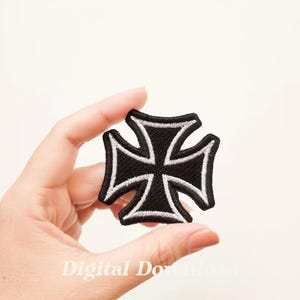 May include: Black iron cross patch with a white outline. The patch is embroidered and has a slightly distressed look.