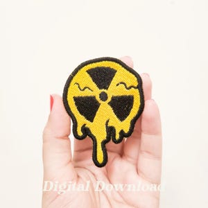 Könnte beinhalten: Gelber und schwarzer gestickter Bügelaufkleber mit einem tropfenden radioaktiven Symbol.