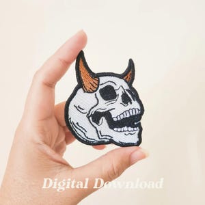 May include: White embroidered skull with orange horns, a black outline, and a toothy grin. The skull is facing right and is a patch.